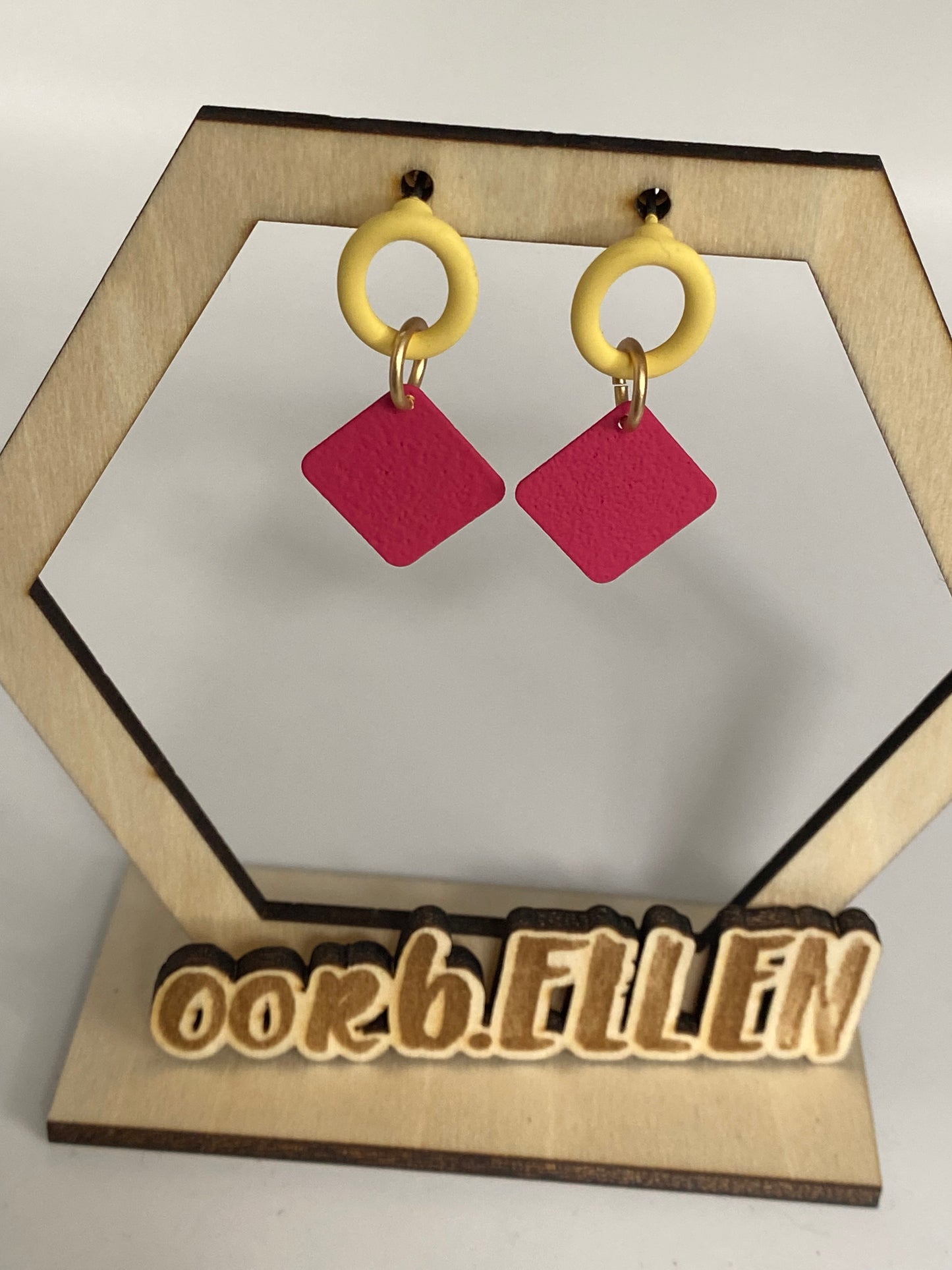 Kleine volle vierkantjes (framboos) aan pastelgele open ovalen oorknoppen