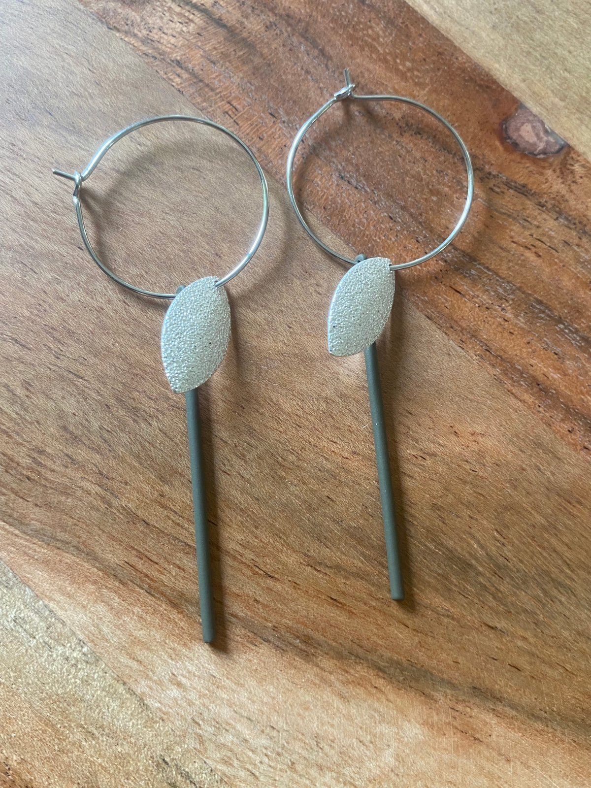 Zilverkleurige blaadjes aan zilverkleurige ringen en bruin staafje