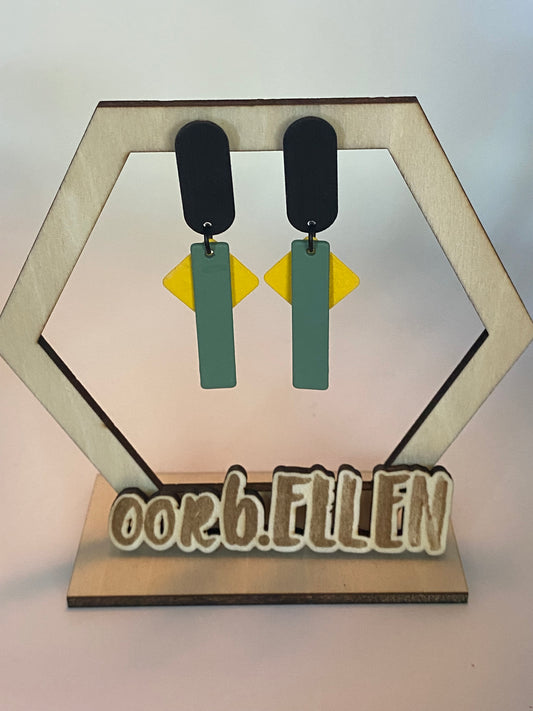 Basilicumgroen staafje en okergeel vierkantje aan zwarte ovalen oorknopjes